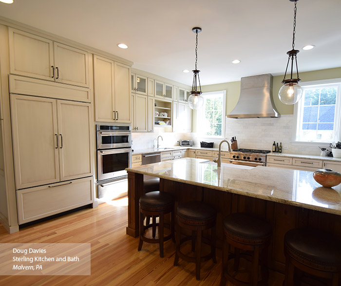 Casual kitchen with off white glazed cabinets and a dark kitchen island