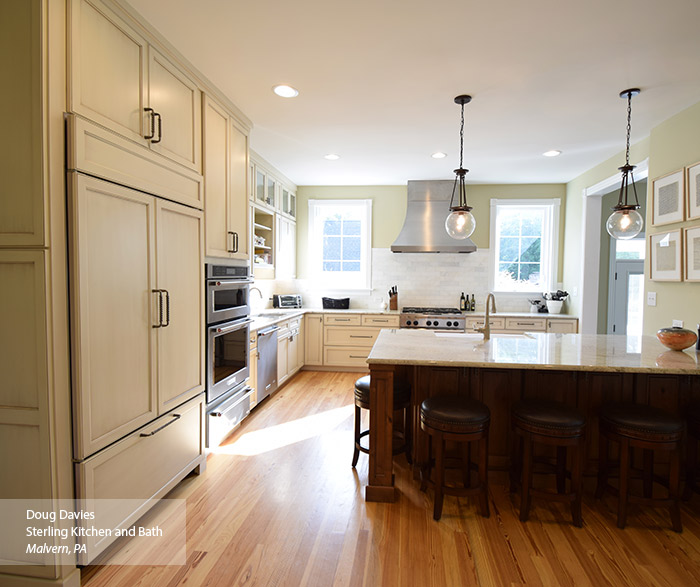 Casual kitchen with off white glazed cabinets and a dark kitchen island